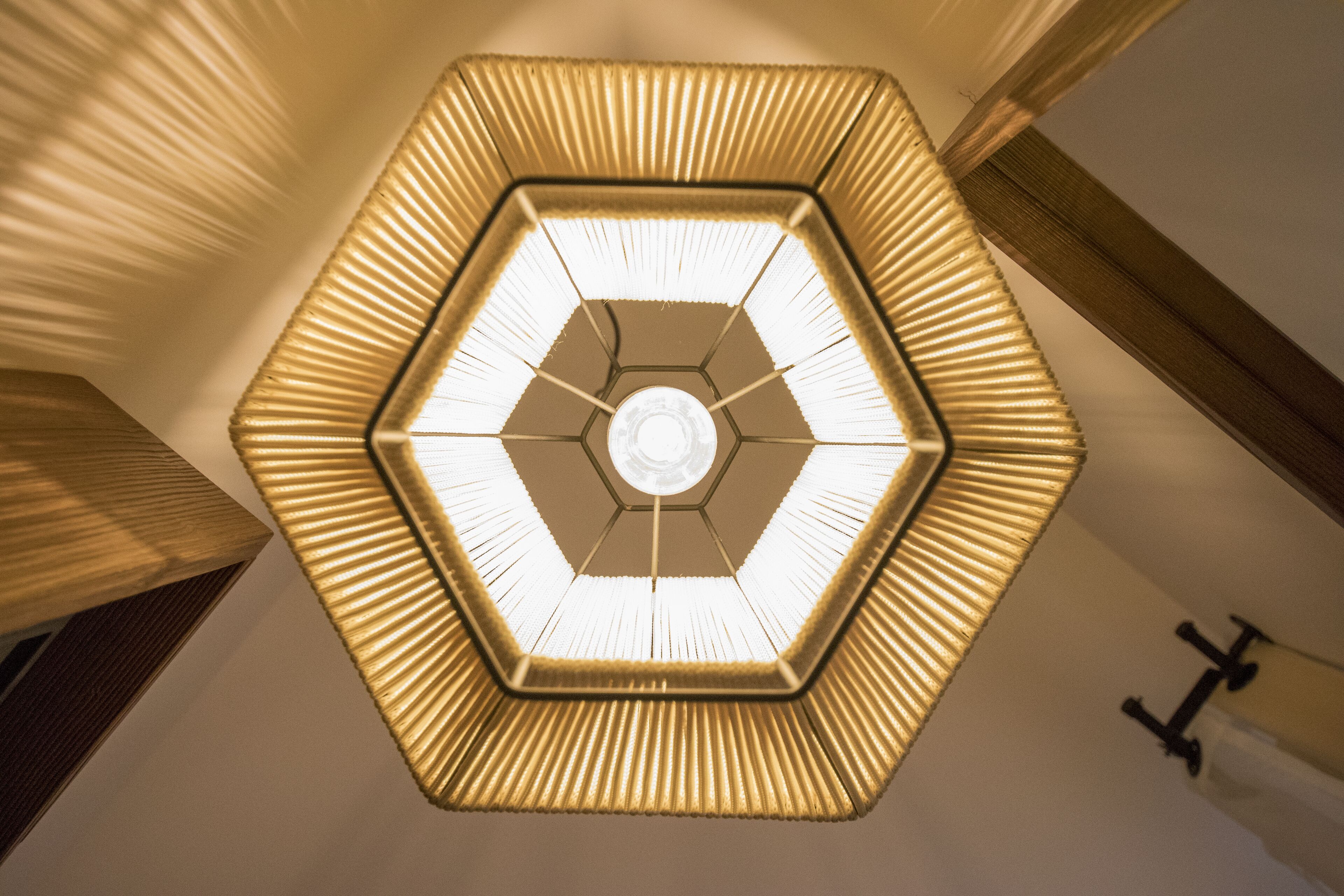A hexagonal ceiling light fixture with a central glass element and a ribbed design.