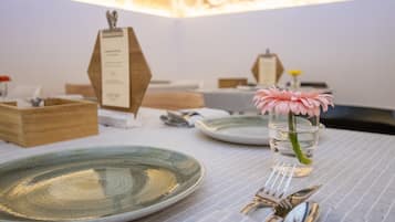 Una mesa de comedor con platos, cubiertos y un florero con una flor.