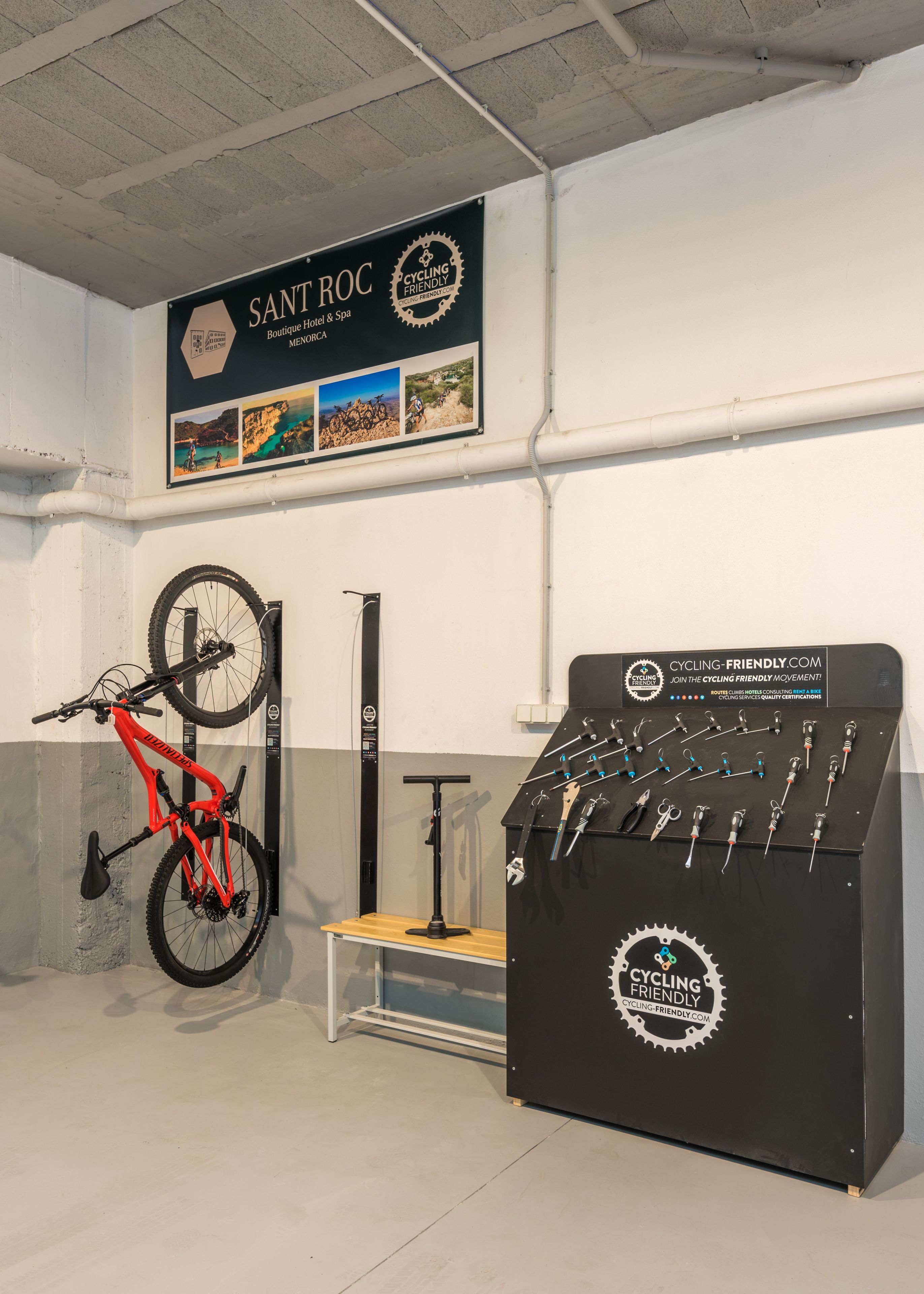 A bicycle leaning against a wall, a bike rack, and a display of cycling tools.