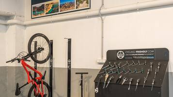 A bicycle leaning against a wall, a bike rack, and a display of cycling tools.