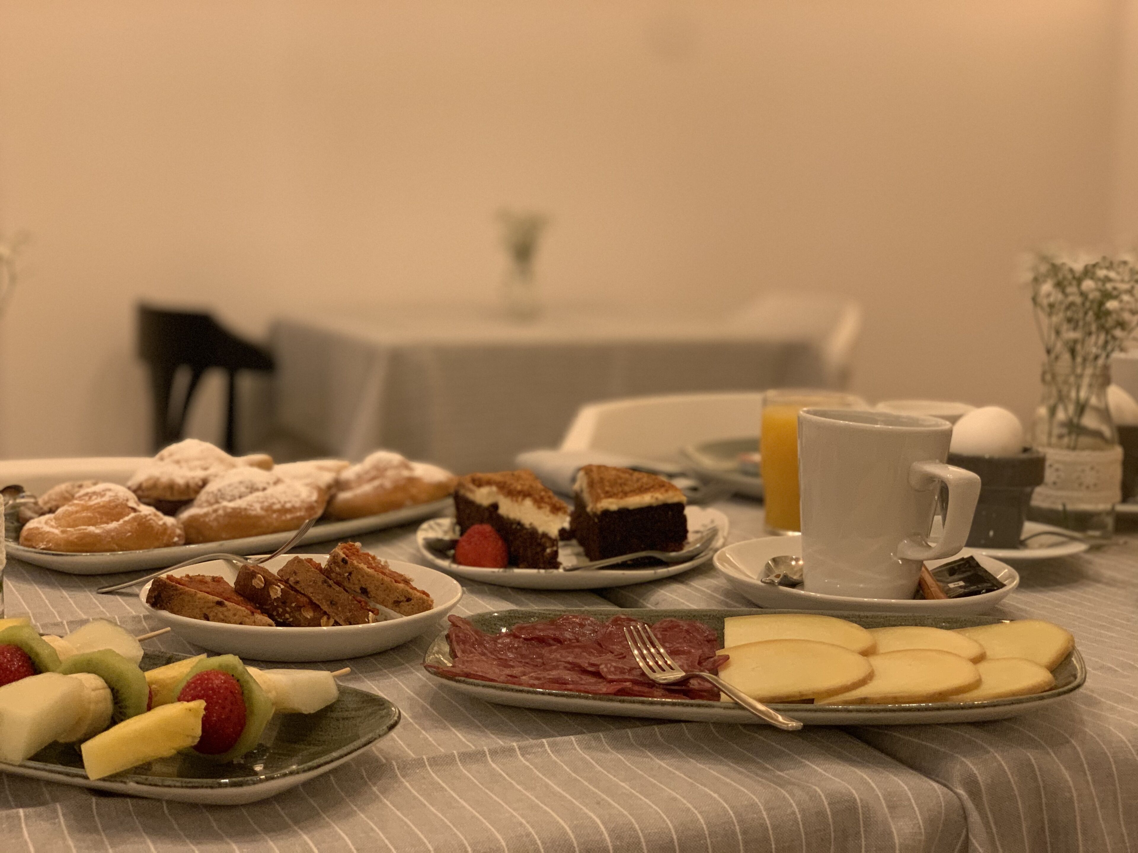 Ett frukostbord med olika sorters bakverk, frukt och en kopp kaffe.