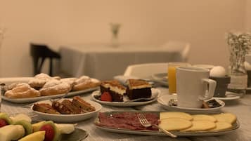 Ett frukostbord med olika sorters bakverk, frukt och en kopp kaffe.