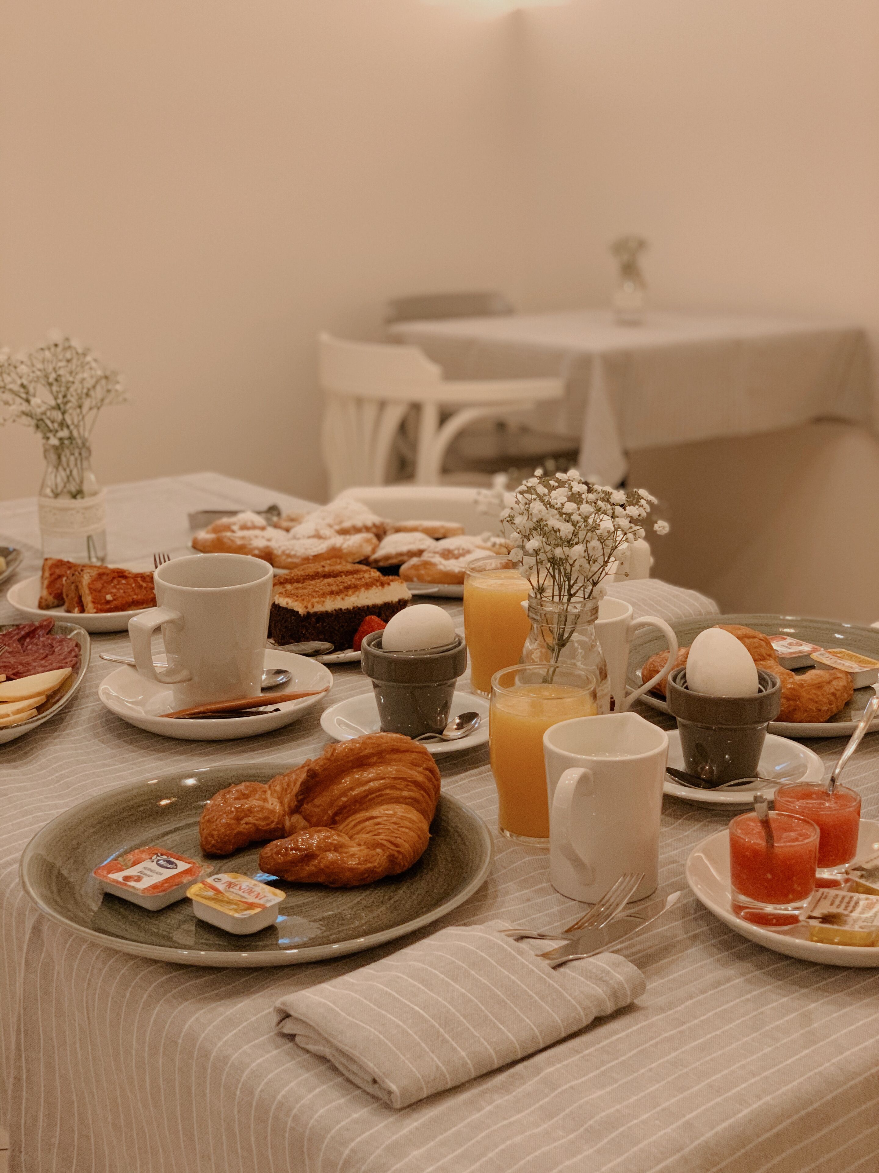 Colazione con croissant, pasticcini e bevande su un tavolo.