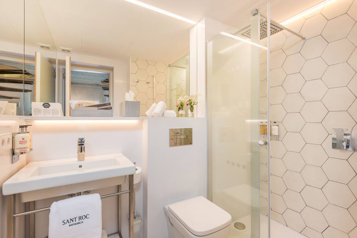 A modern bathroom with a glass shower enclosure, a white sink, and a toilet.