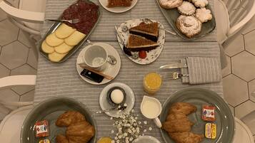 Una mesa de desayuno con diversos alimentos, como pasteles, brochetas de fruta y cruasanes.