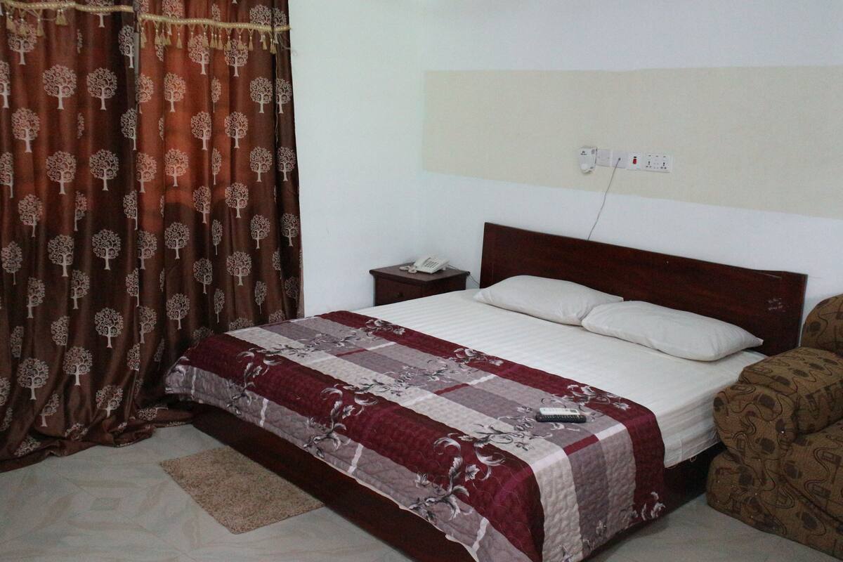 Quarto com cama, mesa de cabeceira, telefone e tomada na parede.