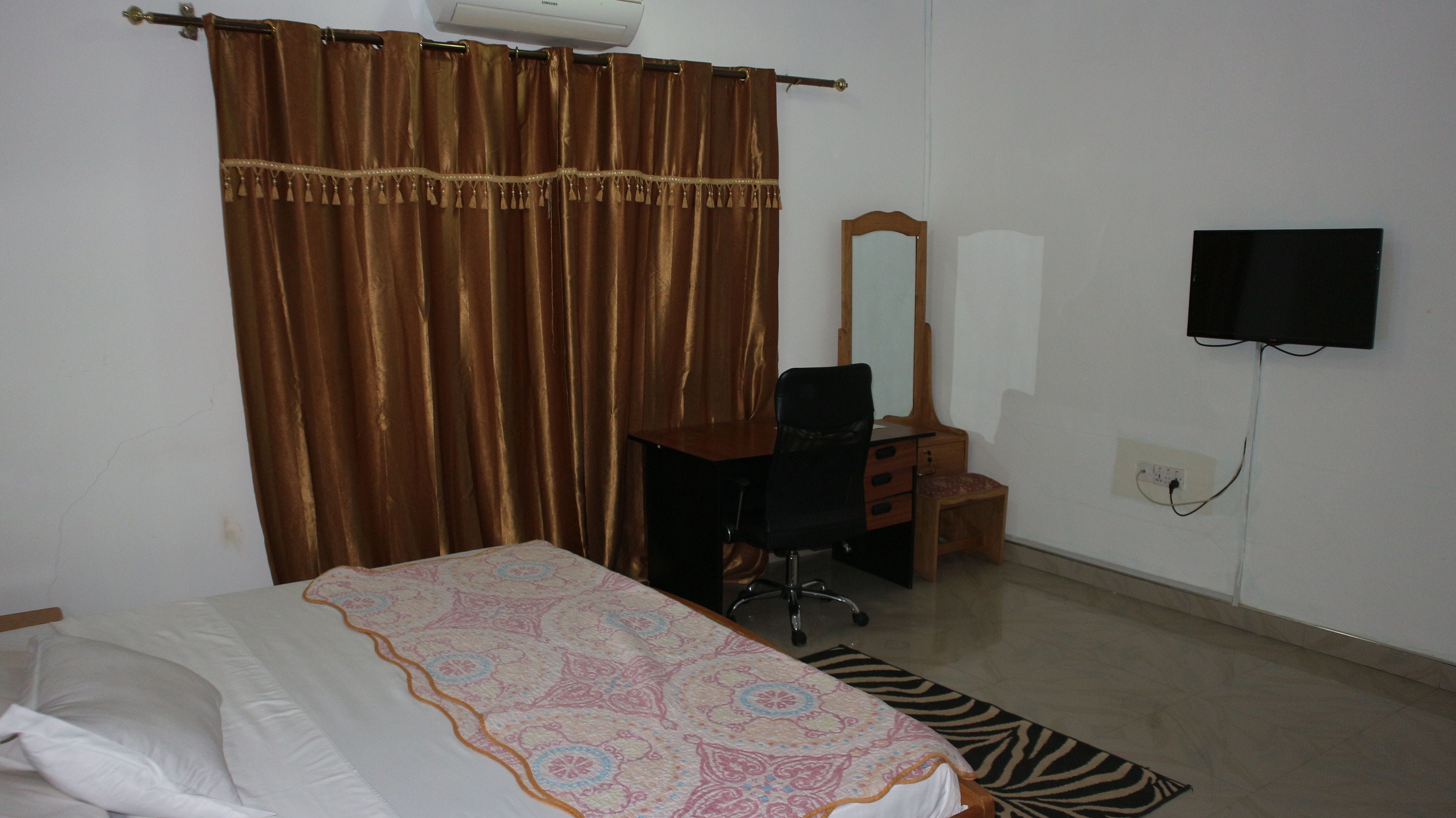 Une chambre à coucher comprenant un lit, un bureau, une chaise, un miroir et un téléviseur.