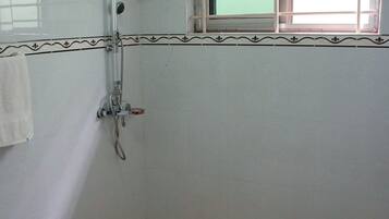A bathroom with a shower, a sink, and a small window.