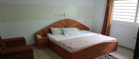 A bedroom with a wooden bed, white bedding, a bedside table with a phone, and a zebra-patterned rug.