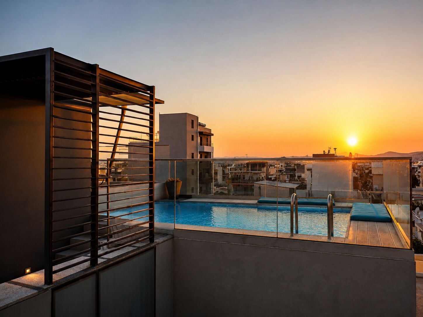 A rooftop pool with a view of the sunset and surrounding buildings.