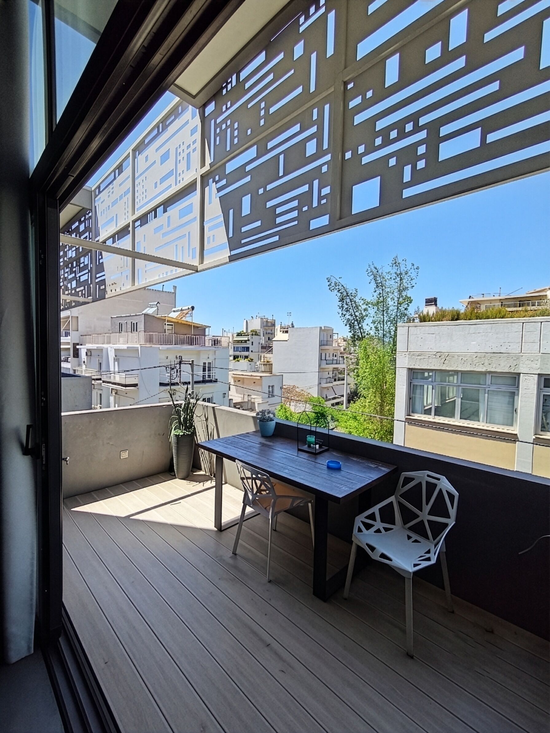 Un balcón con piso de madera, una mesa y dos sillas.