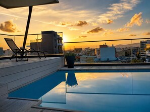 Ein Pool auf dem Dach mit Blick auf die Stadt bei Sonnenuntergang.
