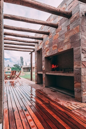 An outdoor patio with a stone fireplace and wooden deck.