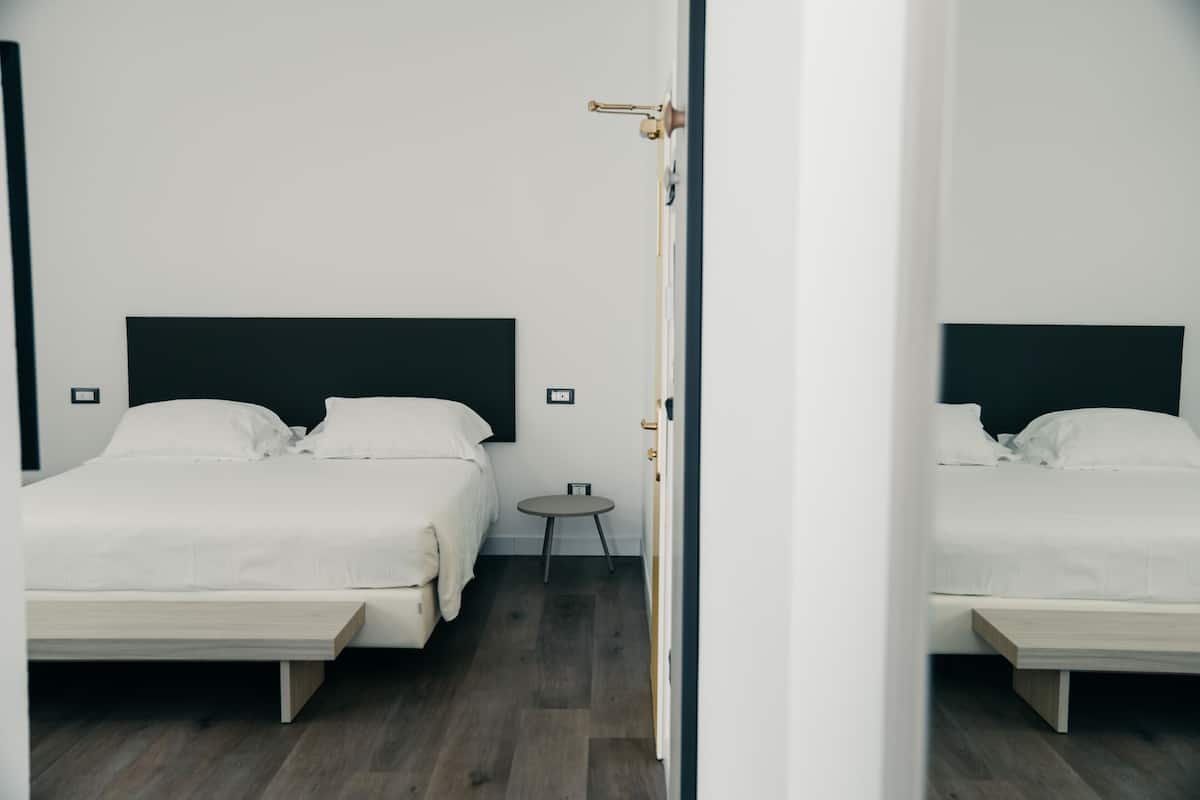 A modern hotel room with a large bed, a small bedside table, and a mirror.