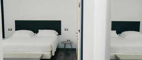 Una habitación de hotel moderna con una cama grande, una mesita de noche y un espejo.