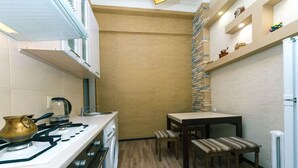 Una cocina compacta con estufa a gas, tetera y una pequeña mesa de comedor con dos sillas.
