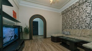Un salón con televisor, sofá, mesa de centro y pared decorada con estampado.