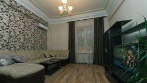 Una sala de estar con un sofá modular, una mesa de centro, un televisor sobre un mueble bajo y una planta.
