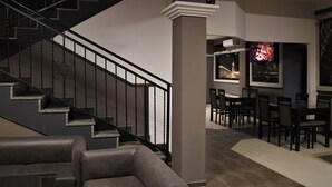 A modern interior with a staircase, a dining area, and a bar.