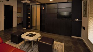 A modern living room with a red sofa, a small coffee table, and a TV mounted on the wall.