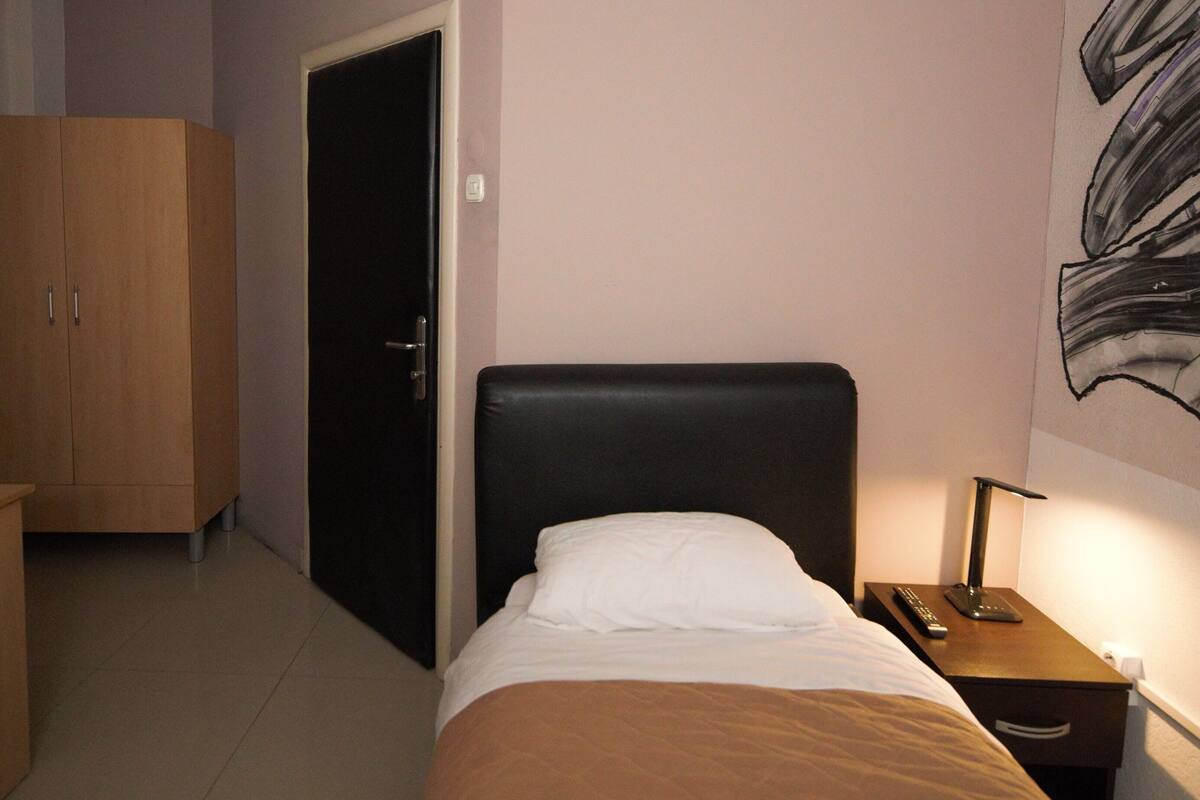 Una habitación de hotel con cama, mesita de noche, escritorio y armario.
