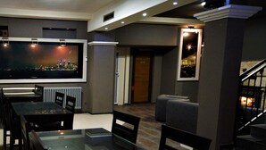 A modern dining area with a glass table and chairs, a large flat-screen TV, and a fireplace.