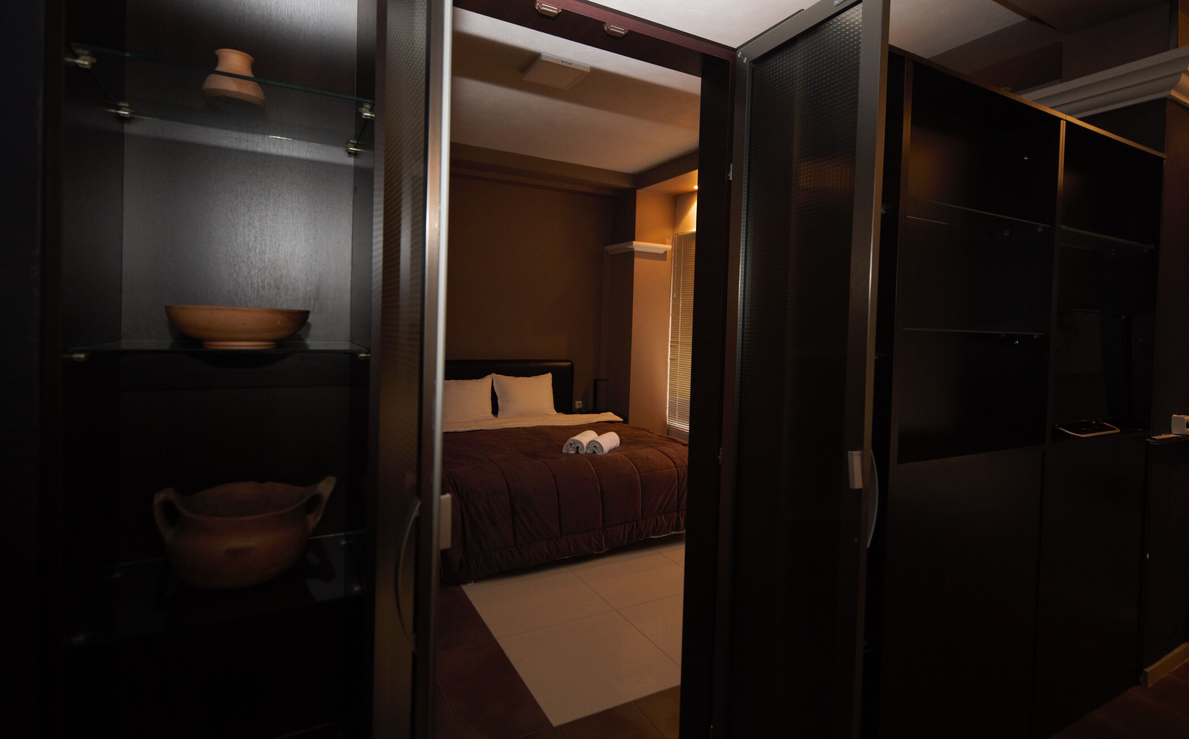 A hotel room with a bed, a small table with a bowl, and a wardrobe.