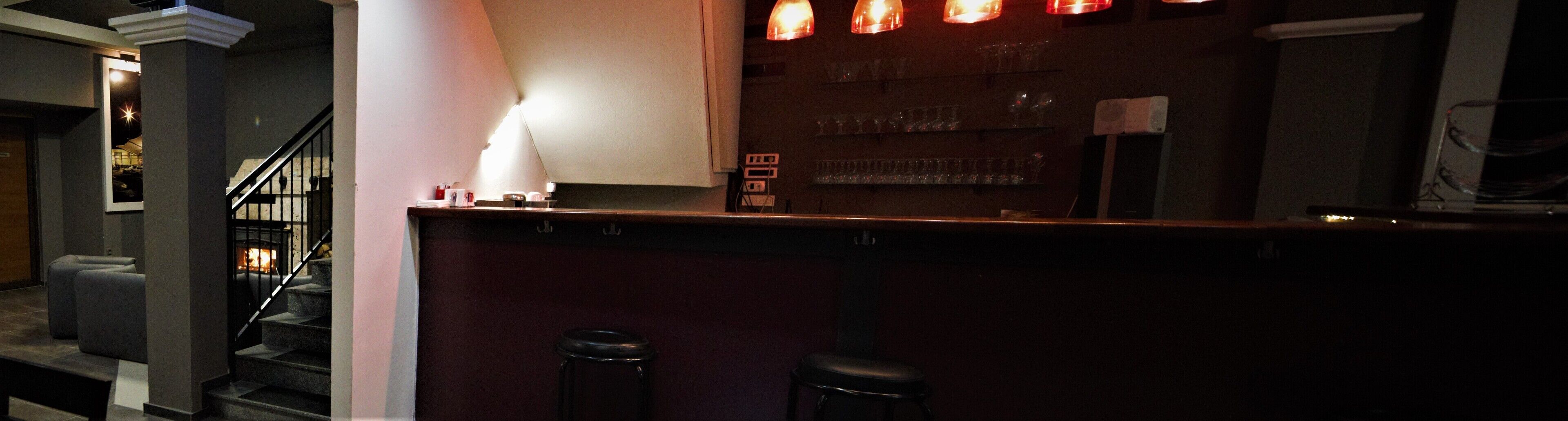 A bar area with a counter, stools, and a staircase leading to an upper level.
