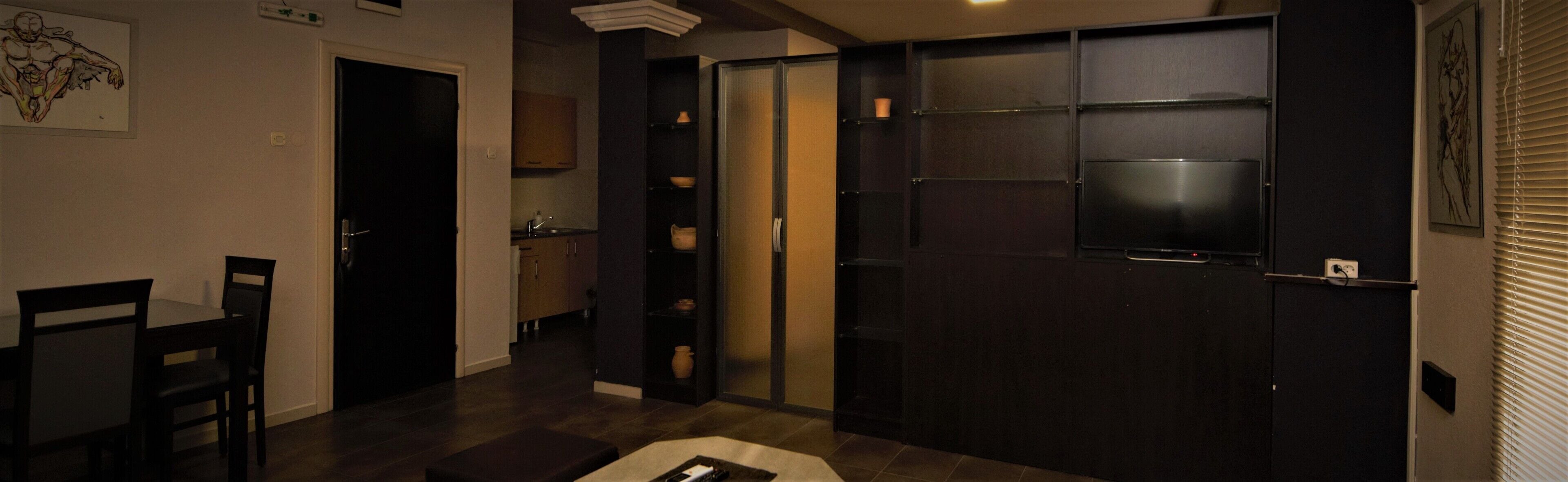 A modern hotel room with a dark wood door, a small window, and a tiled floor.