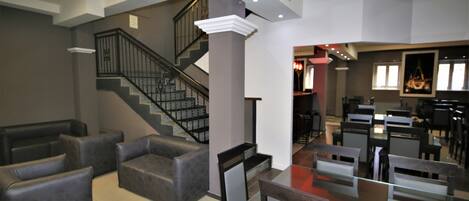 A spacious living area with a staircase, leather sofas, and a dining area with glass-top tables and chairs.