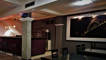 A bar area with stools, a counter, and a large screen displaying a bridge.