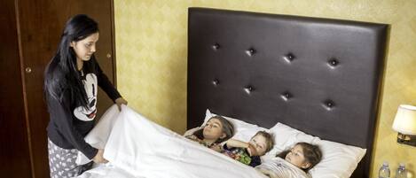 A hotel room with a large bed, a bedside table with a lamp, and a wardrobe.