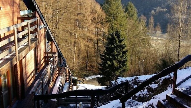 A wooden staircase leading to a building with a view of a forested valley. - Domaine Les Hochets (Vresse-sur-Semois)