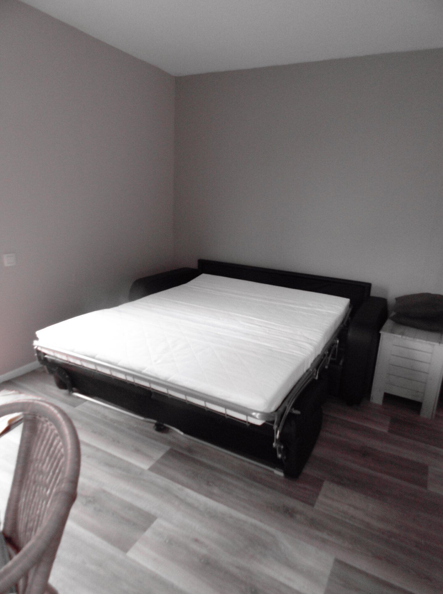 A bedroom with a bed, a chair, a nightstand, and a dresser.