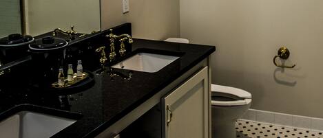A bathroom with two sinks, a toilet, and a mirror.