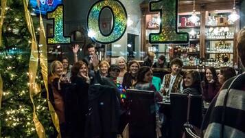 A group of people gathered around a bar area with a Christmas tree and festive decorations.