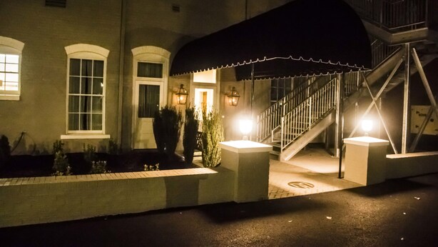 A building with a covered entrance, a staircase, and a well-lit facade. - The Meadows Hotel (Fulton)
