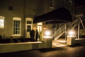 A building with a covered entrance, a staircase, and a well-lit facade. - The Meadows Hotel (Fulton)
