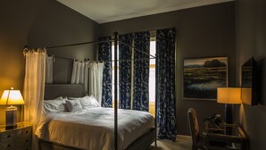 A four-poster bed with a canopy, a bedside table with a lamp, a chair, and a painting on the wall. - The Meadows Hotel (Fulton)