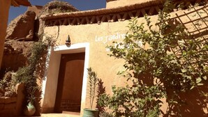 Une cour avec une porte, des plantes en pot et un mur orné d’inscriptions.