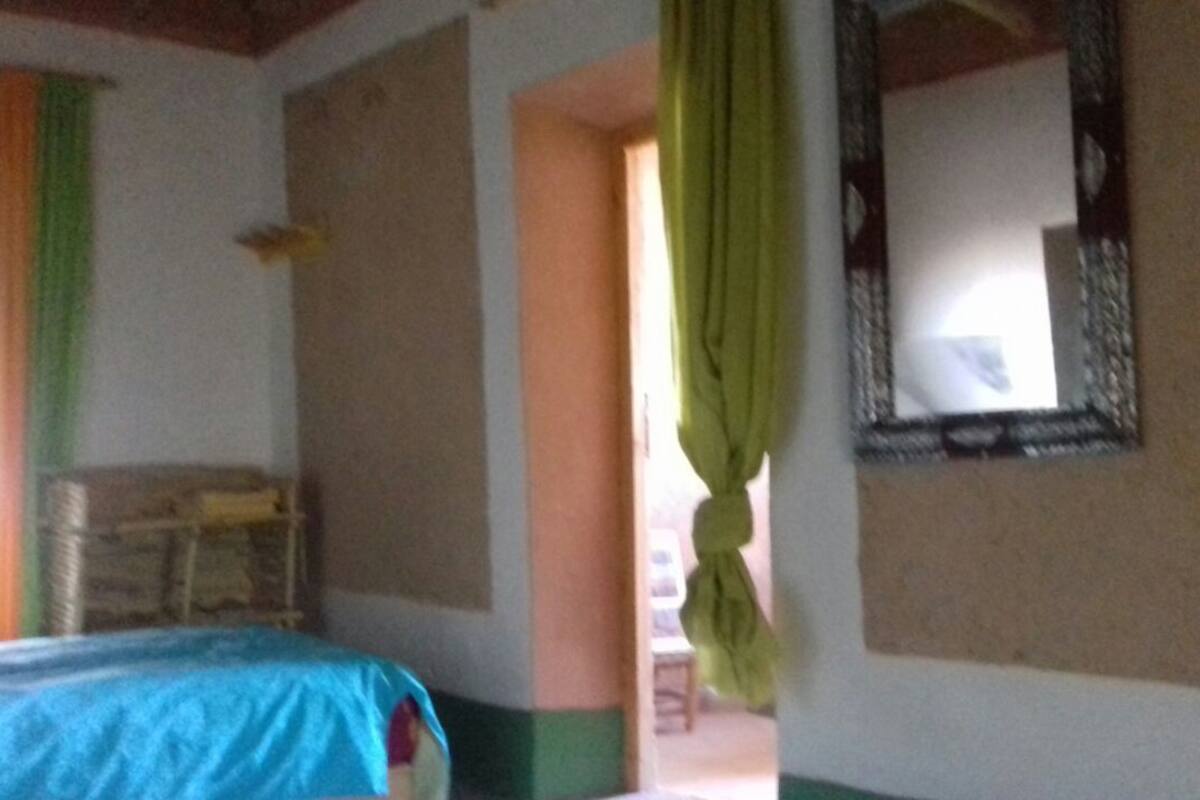 A room with a bed, a mirror, and a window with curtains.