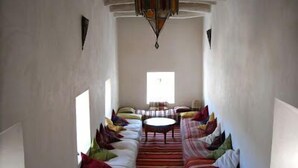 Une pièce avec un long canapé, une table basse ronde et un tapis à motifs.