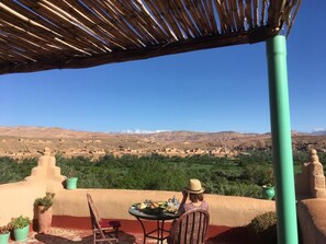Una terraza con mesa y sillas, con vista a un paisaje montañoso.