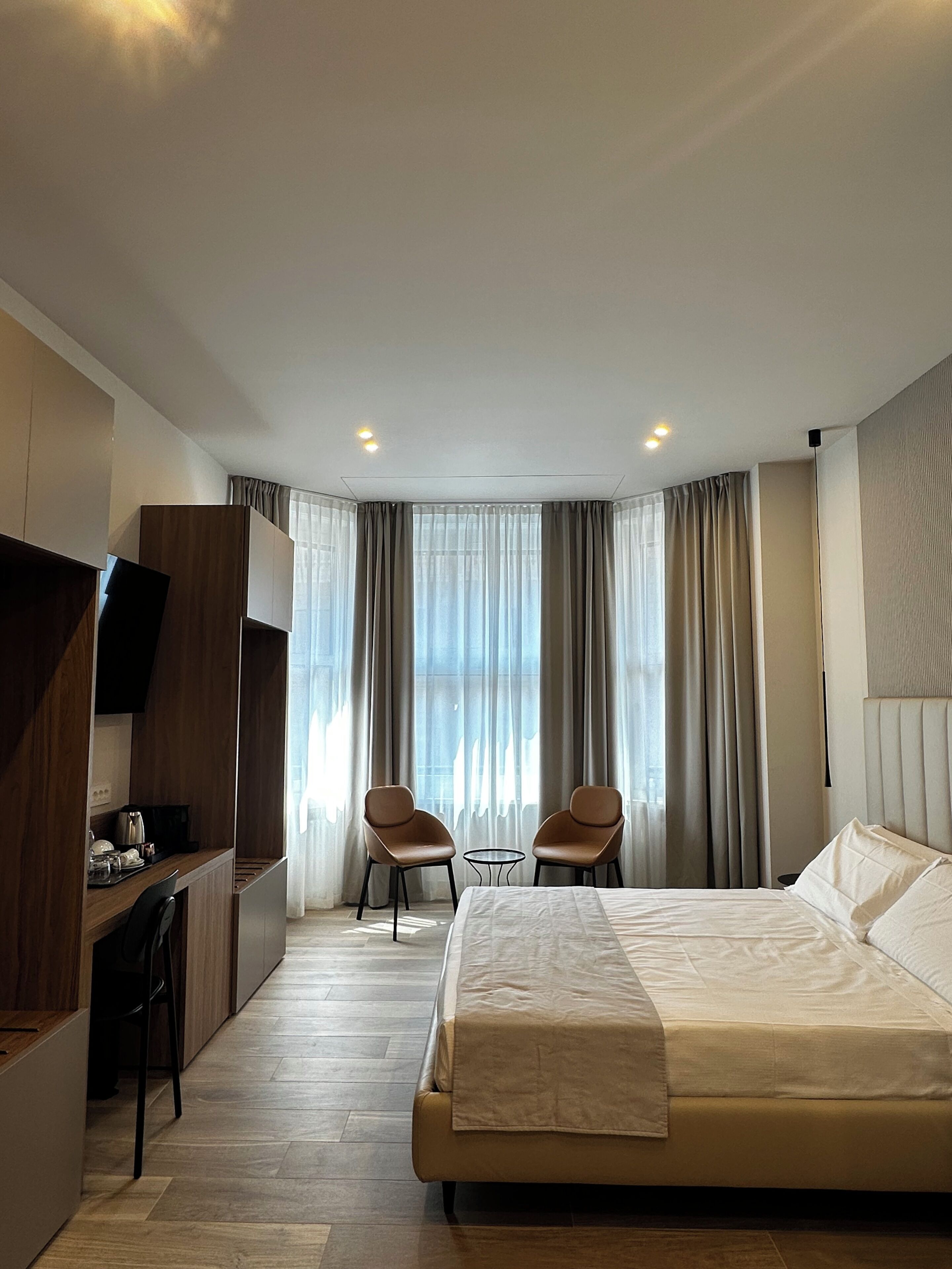 Une chambre d’hôtel comprenant un lit, deux chaises, un bureau et un téléviseur.