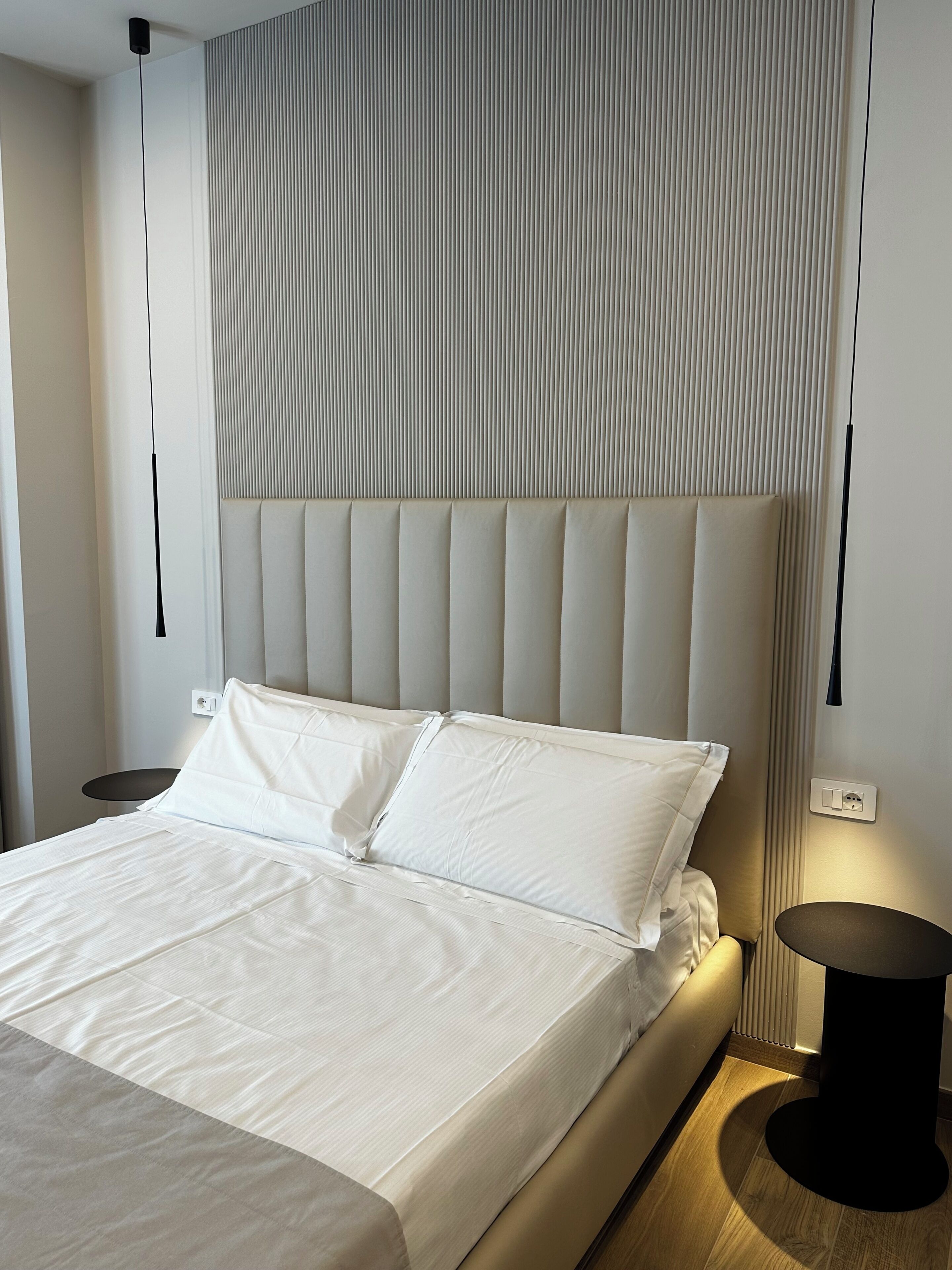 Ein modernes Hotelzimmer mit einem großen Bett, einem Nachttisch und einer Wandleuchte.