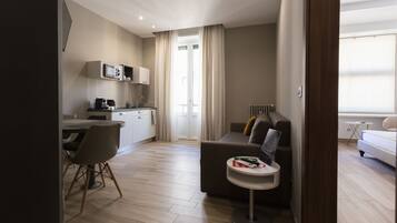 Eine moderne Wohnung mit Essbereich, Küchenzeile und Wohnzimmer mit Sofa und kleinem Beistelltisch.