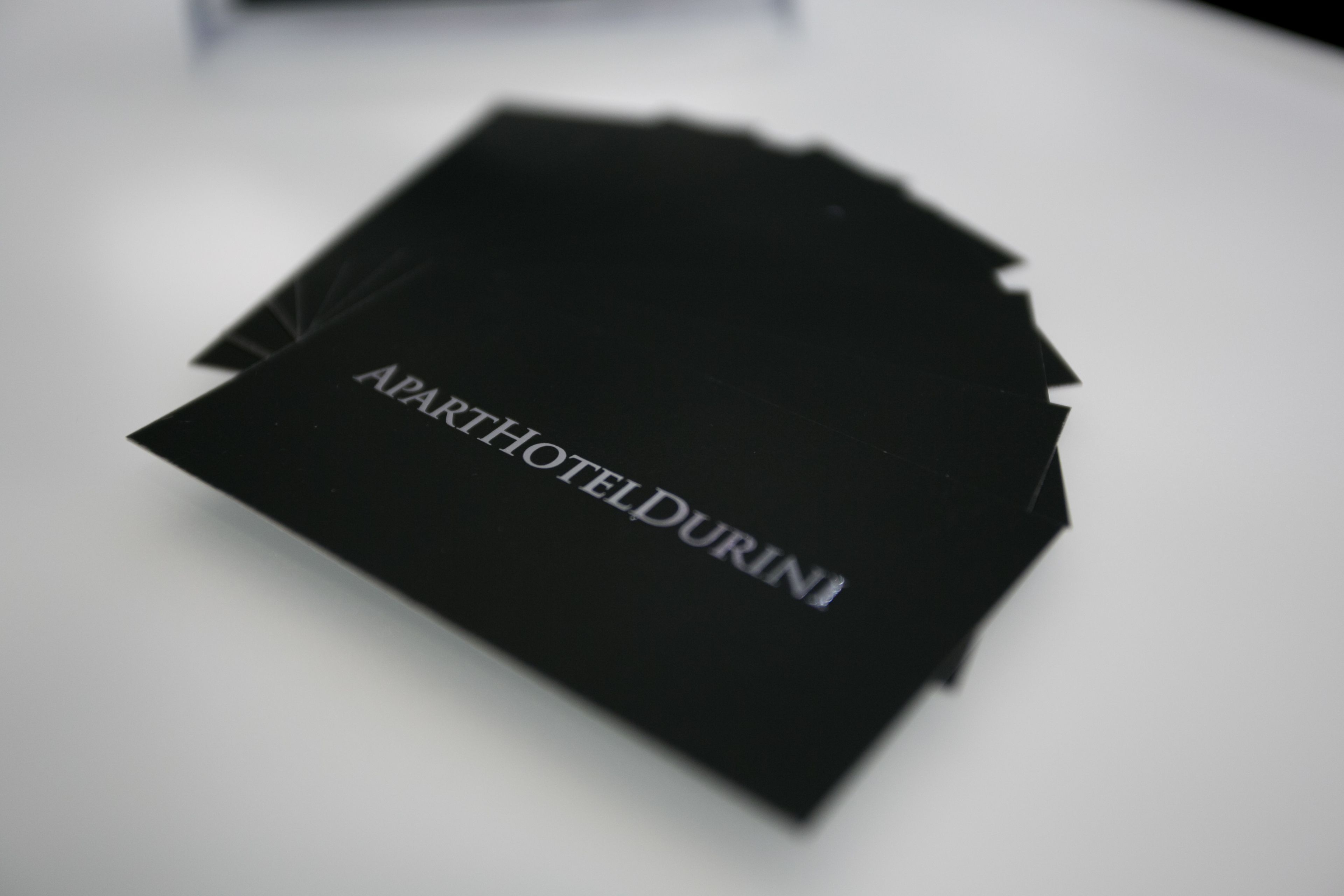 A stack of black business cards with the text "APARTHOTELDURINI" on them.