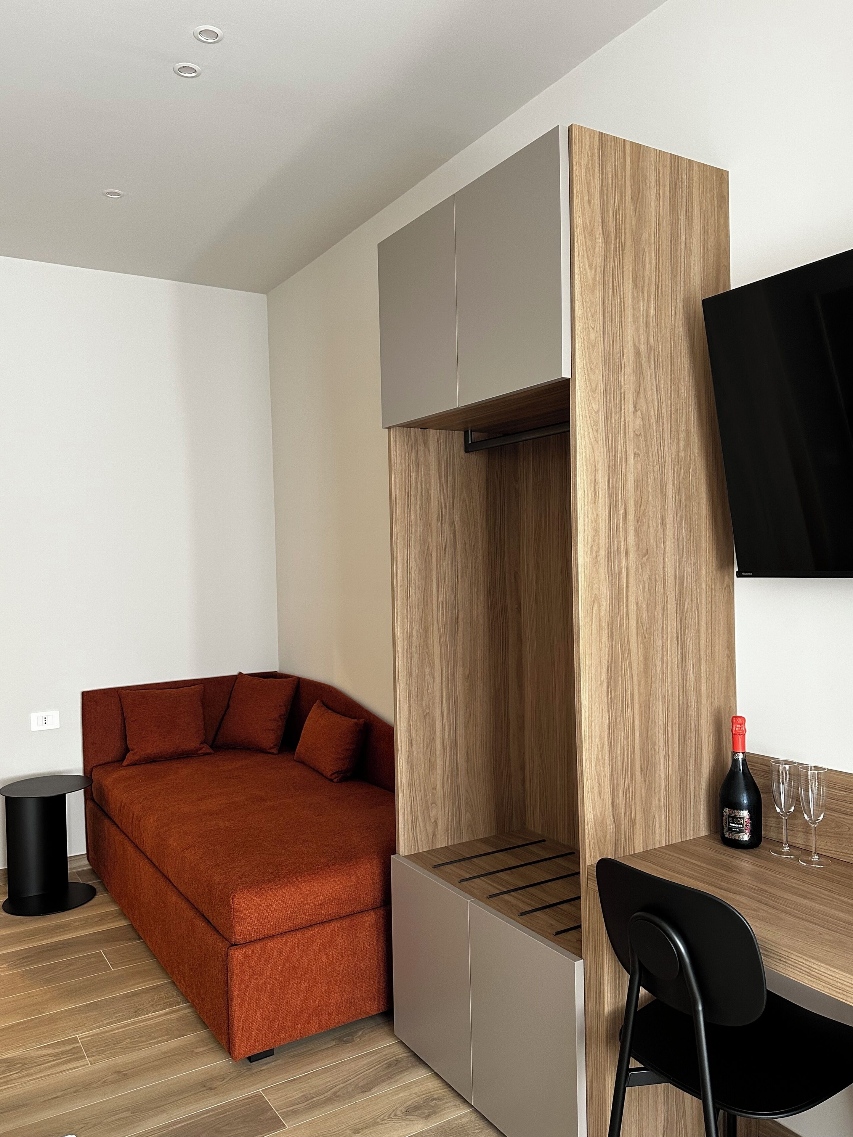 Een moderne kamer met een bank, een eettafel en een aan de muur bevestigde televisie.
