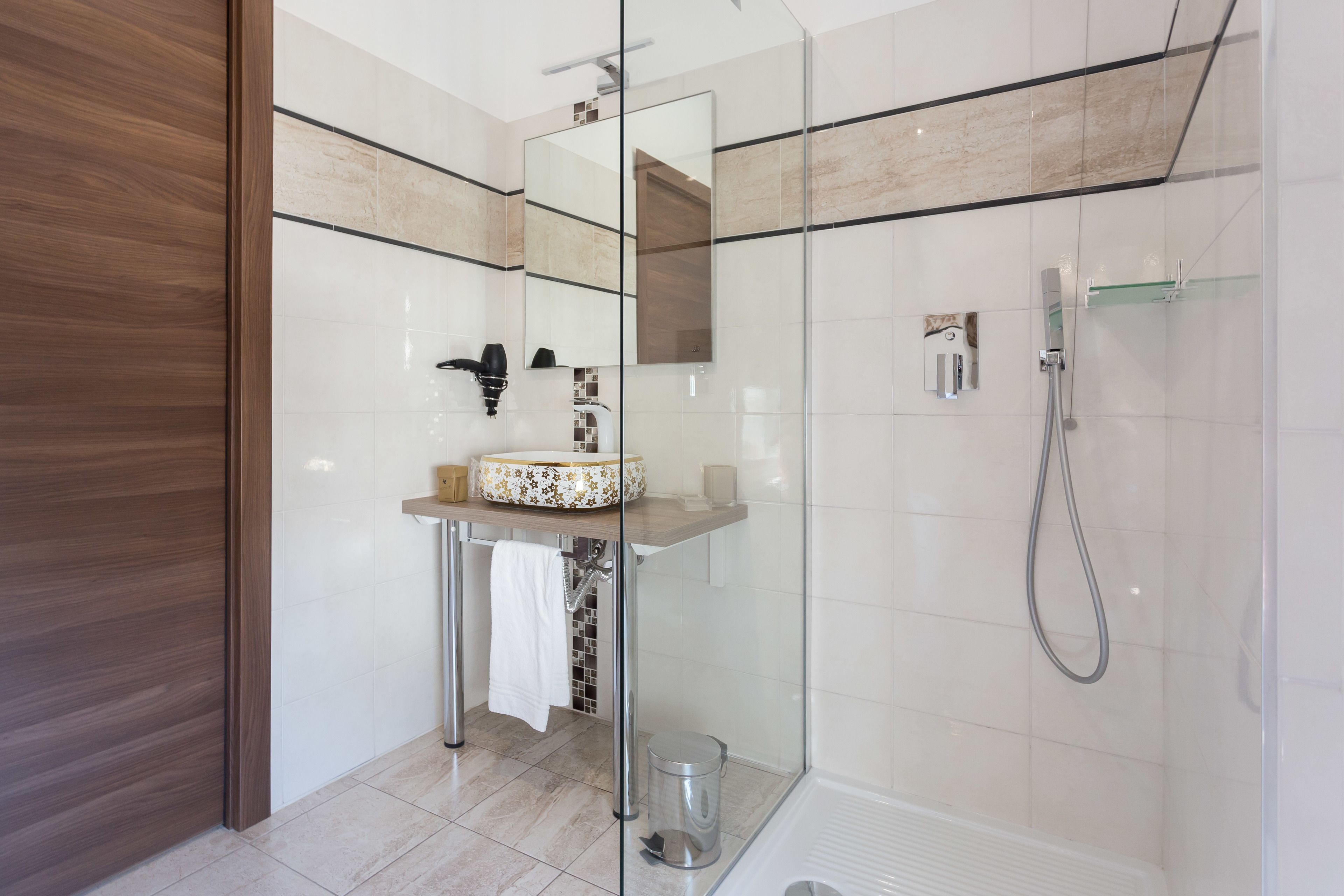 Une salle de bain moderne avec une douche à parois de verre, un meuble-lavabo en bois et un grand miroir.