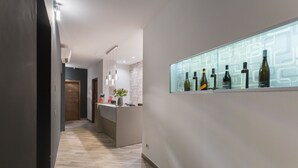 Un hall d’entrée moderne avec un plancher en bois, un comptoir d’accueil et un présentoir à vin fixé au mur.